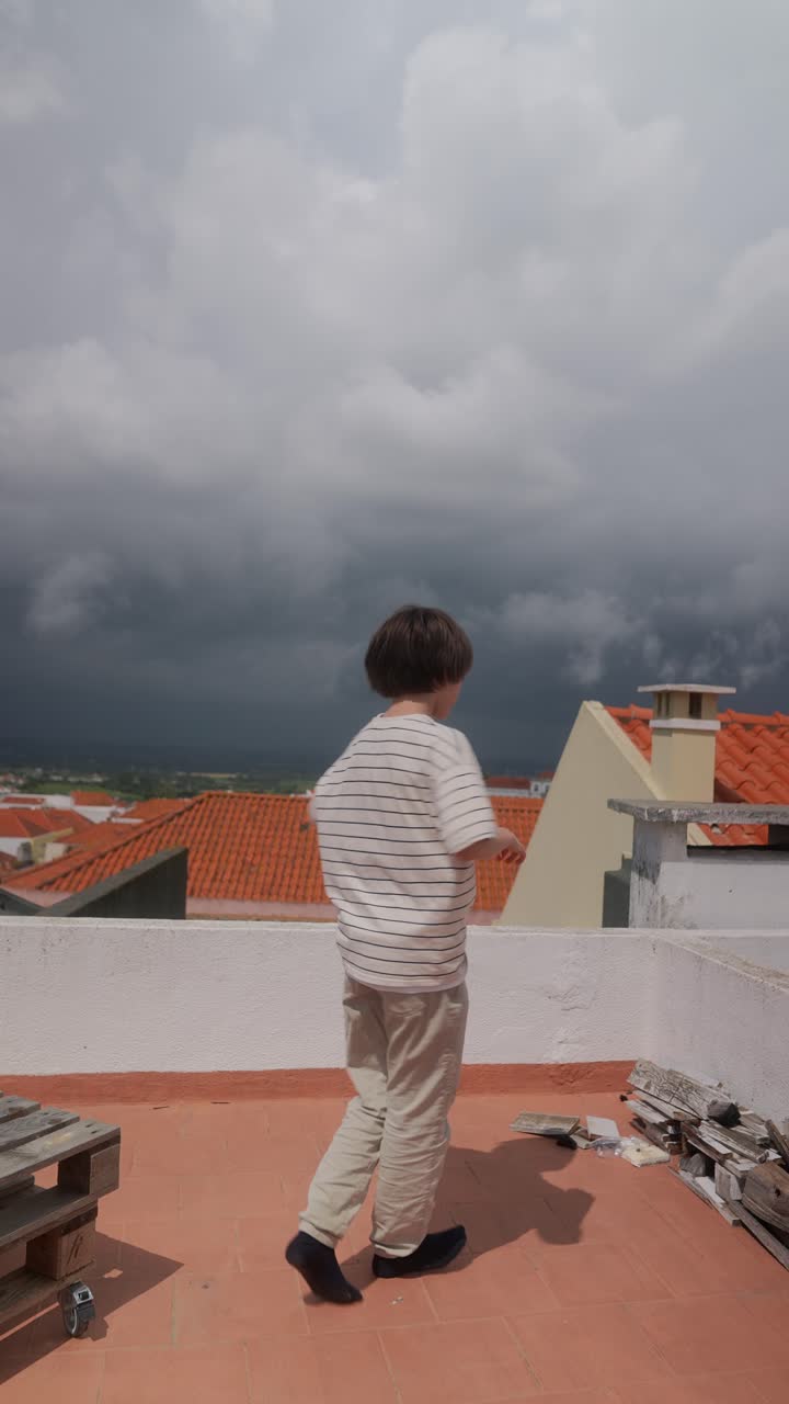 Boy Dancing on a Rooftop on a Cloudy Day
