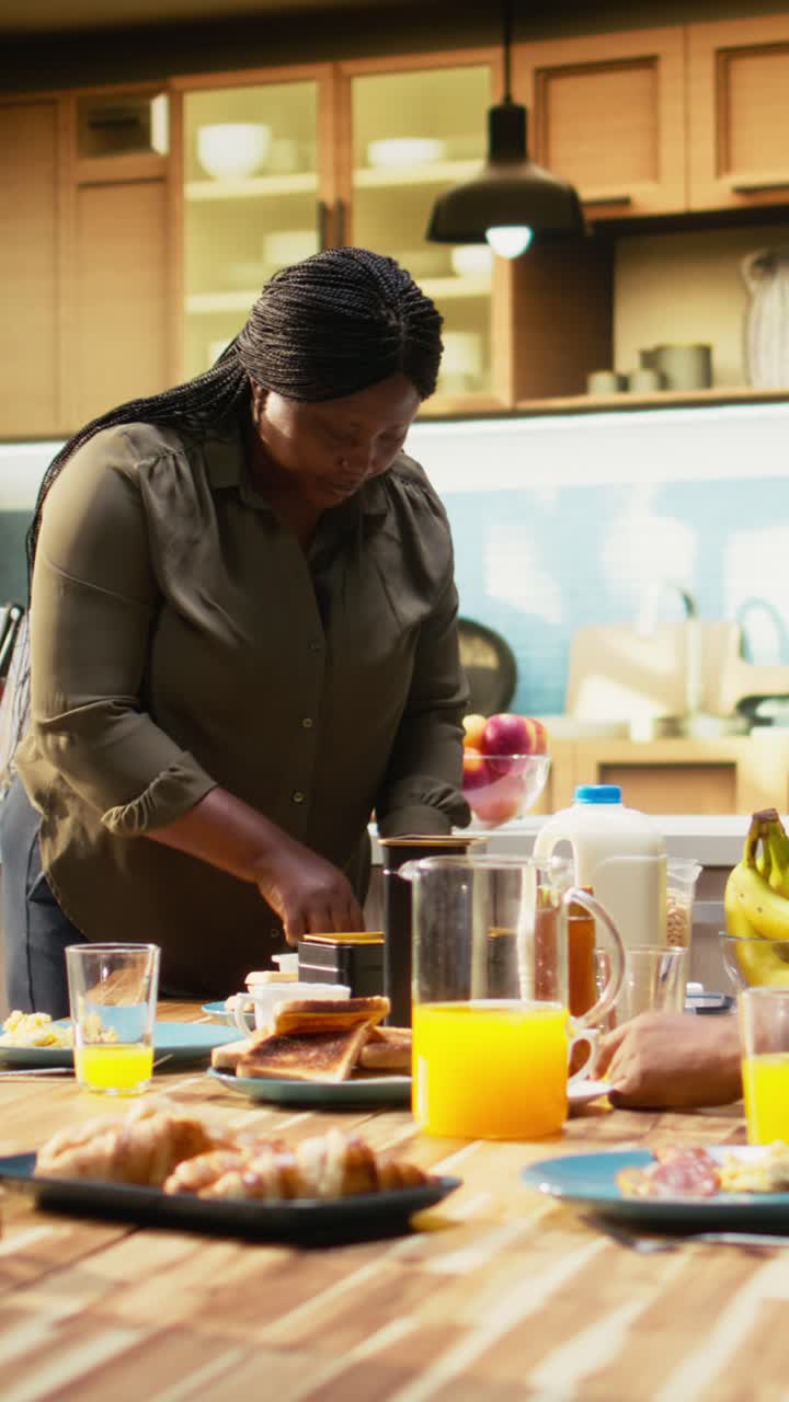 Vertical Video Black woman preparing lunch box for her school girl daughter during breakfast
