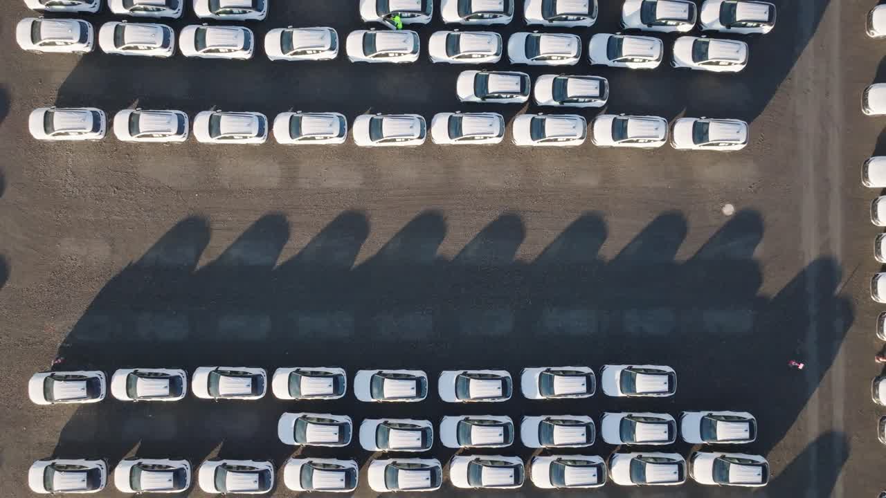 Aerial top down ascend over parking lot full with manufactured cars