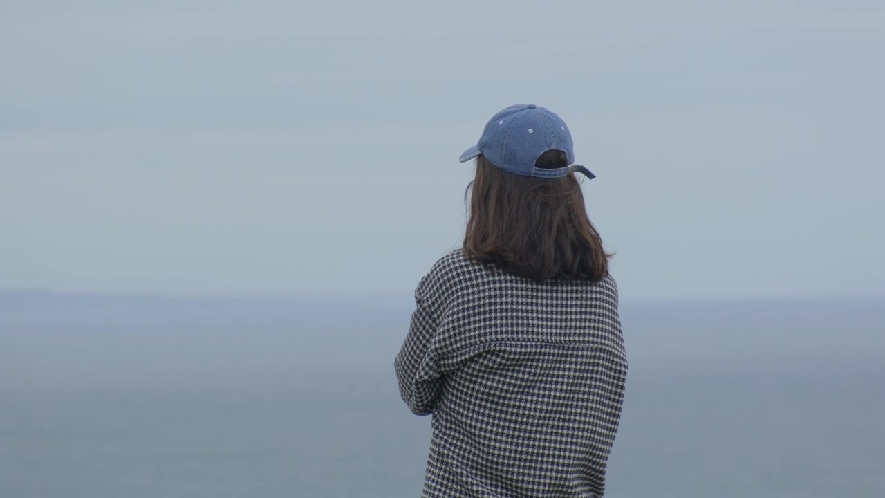 Mulher em pé no topo de um penhasco, apreciando uma vista deslumbrante ao amanhecer.