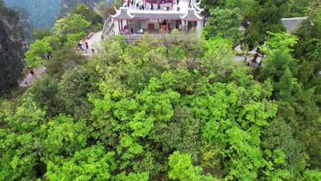 Eine-Drohne-Senkt-Sich-Vor-Dem-Liuqi-Pavillon-Und-Entdeckt-Menschen,-Die-Mitten-Im-Wald-Ankommen