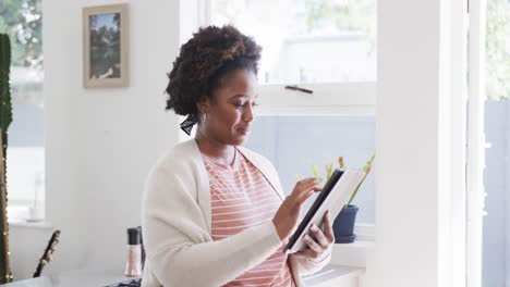 Porträt-Einer-Glücklichen-Afroamerikanischen-Frau-Mit-Tablet,-Die-Zu-Hause-In-Der-Sonnigen-Küche-Steht,-Zeitlupe