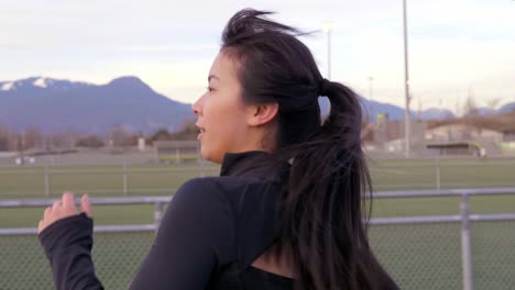 asian woman in workout clothes running on athletics track