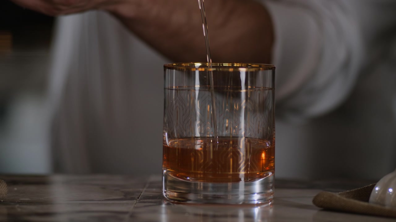 Bartender strains an old fashioned into a cocktail glass