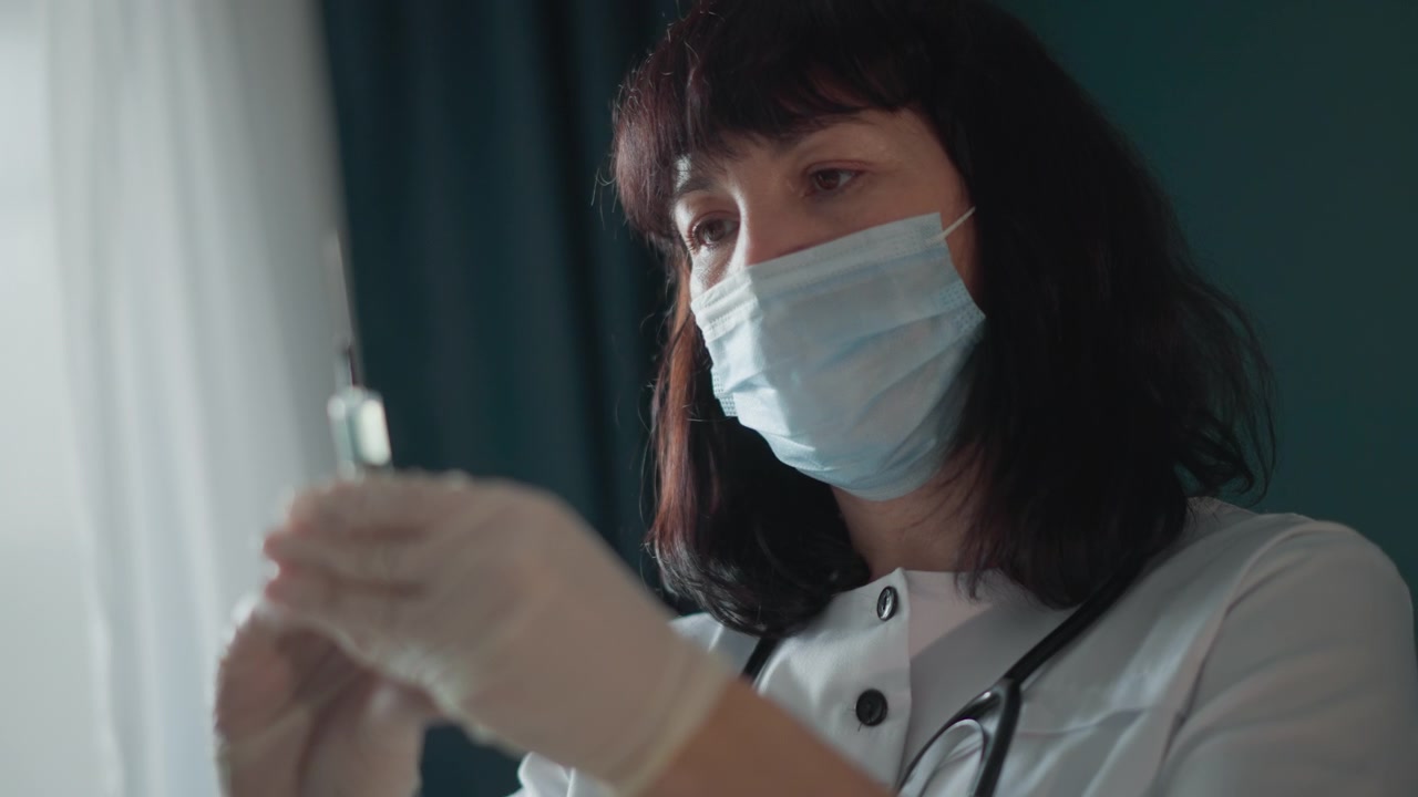 Doctor administers injection carefully. Nurse or doctor setting up injection with precision and care. Medical personnel carefully readying syringe for patient treatment in clinical environment
