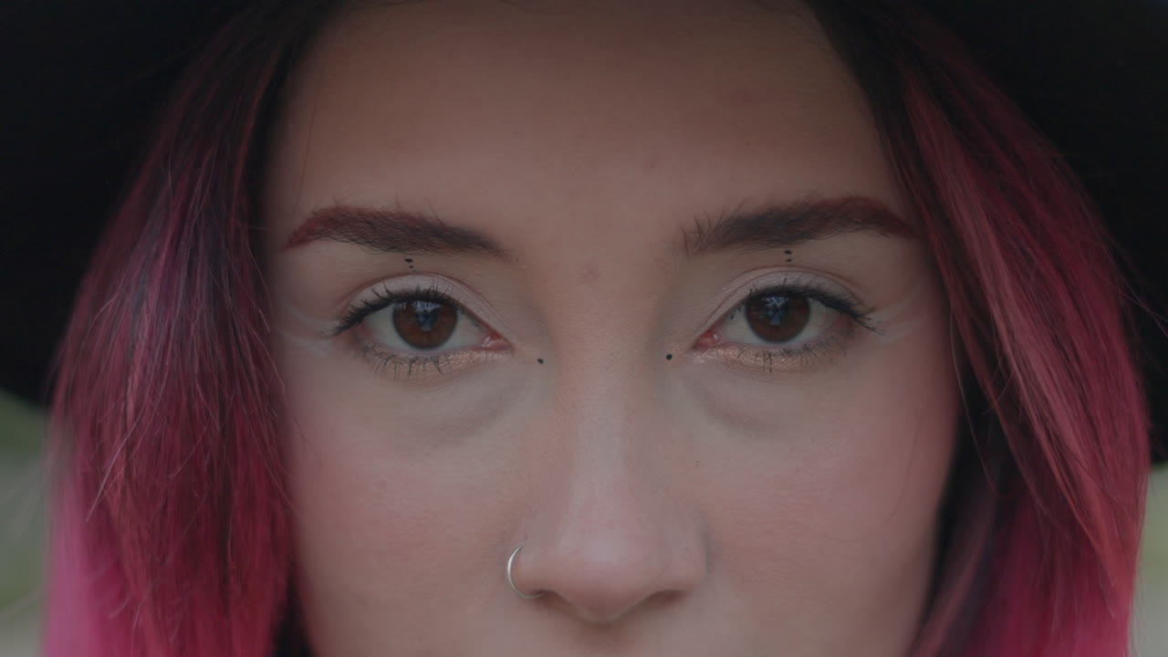 Close-up portrait of a woman with pink hair and a hat