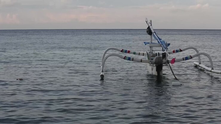 Badik boats float on the waters of Nusa Penida, Bali ahead of sunset