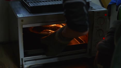 baking pot with lid pushed into oven and closed inside, filmed as medium closeup shot in slow motion