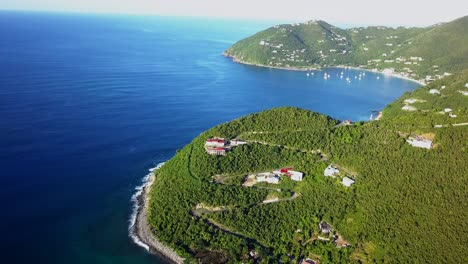 un dron vuela en una toma de una gran casa junto a un acantilado en la isla virgen británica de tortola a media distancia