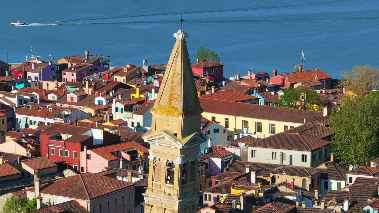 Aerial drone view of the Church of Saint Martin Bishop surrounded by colourful houses in Burano Island, Italy