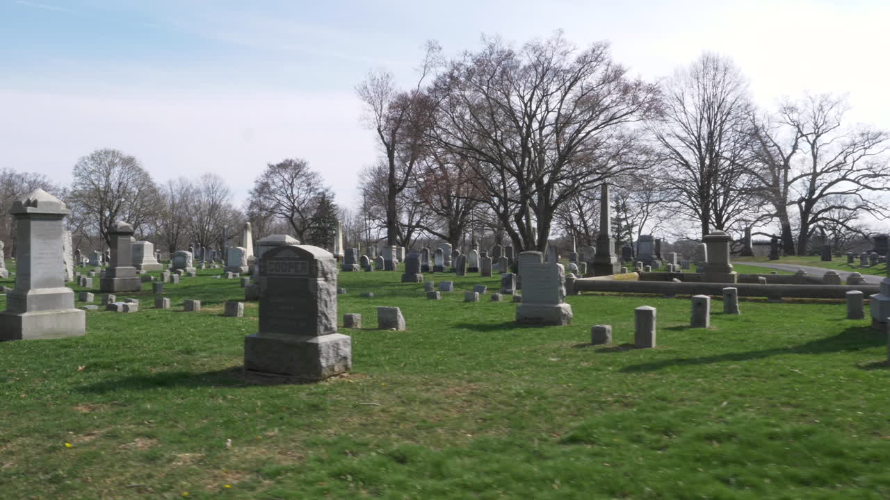 SLOW MOTION : Driving slowly by rows of old headstones through a cemetery on a beautiful day