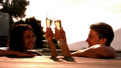 Pareja-Feliz-Bebiendo-Champán-Juntos-En-La-Piscina