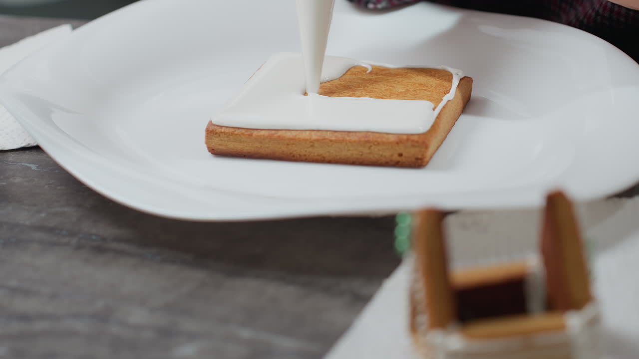 유리 판에 있는 쿠키의 클로즈업이 정확하게 얼어붙고, 전면에 꾸며진 쿠키 하우스가 흐릿하고, 쿠키 가장자리를 는 매끄러운 색 글래스팅이 있습니다.