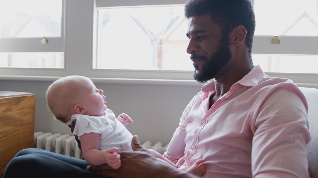 Loving Father Playing With Smiling Baby Daughter Lifting Her In The Air At Home