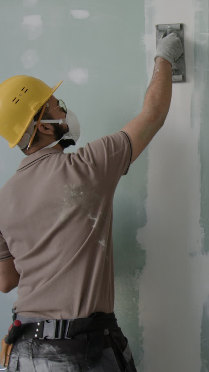 Drywall Worker Sanding a Wall