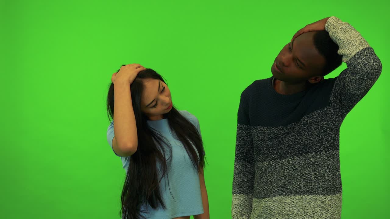 A young Asian woman and a young black man stretch - green screen studio