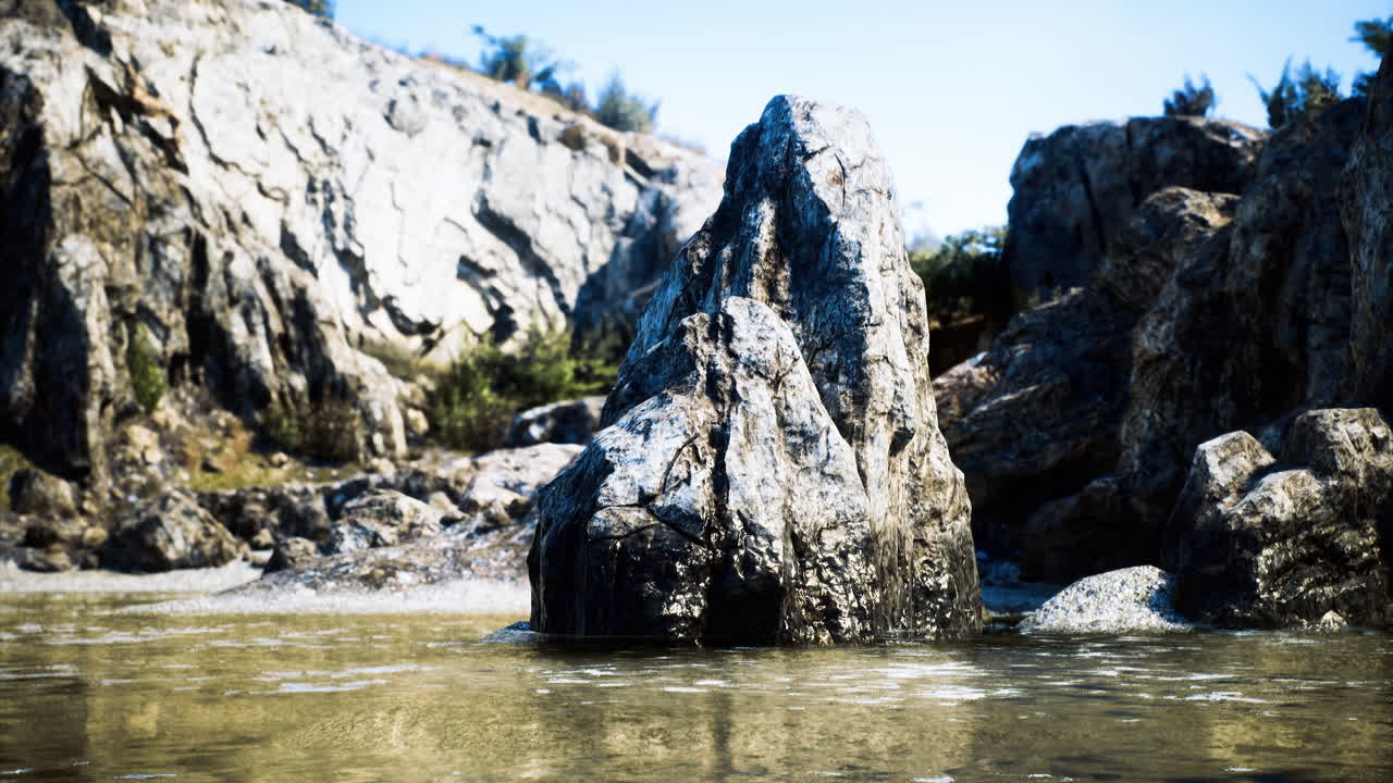 Large rocky formation stands in shallow water at a coastal location