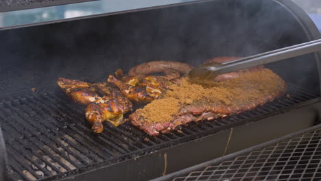 tongs move brown sugar rub over rack of rib in bbq pit