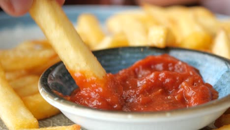 close-up of a french fry being dipped in ketchup