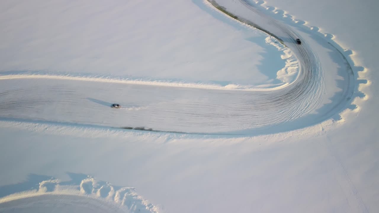 Billige sportsvogne drifter på en frossen sø i Finland under den gyldne time – Vinterlandskab fra luften med en frossen racerbane i høj højde