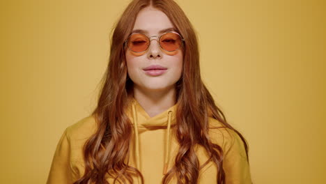 pretty girl looking at camera indoors. woman acting at lens on orange background