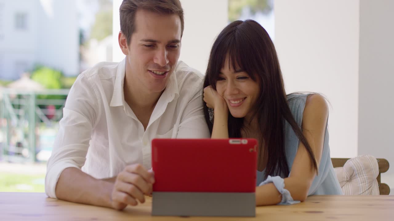 una pareja sonriente usando una tableta juntos