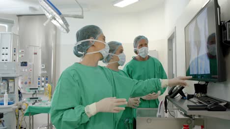 diverse surgeons wearing surgical gowns looking at x-ray scans in operating theatre, slow motion