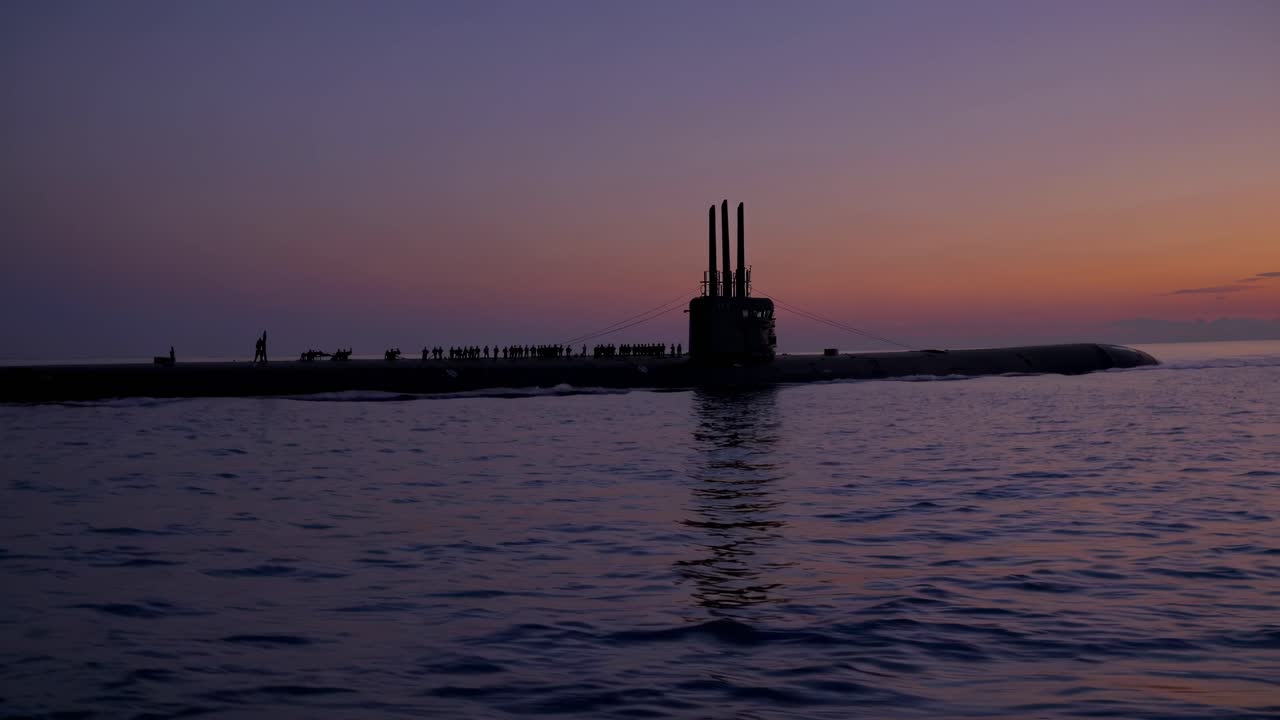 En ubådssilhuet ved solnedgang, fanget fra en lav engel over roligt vand
