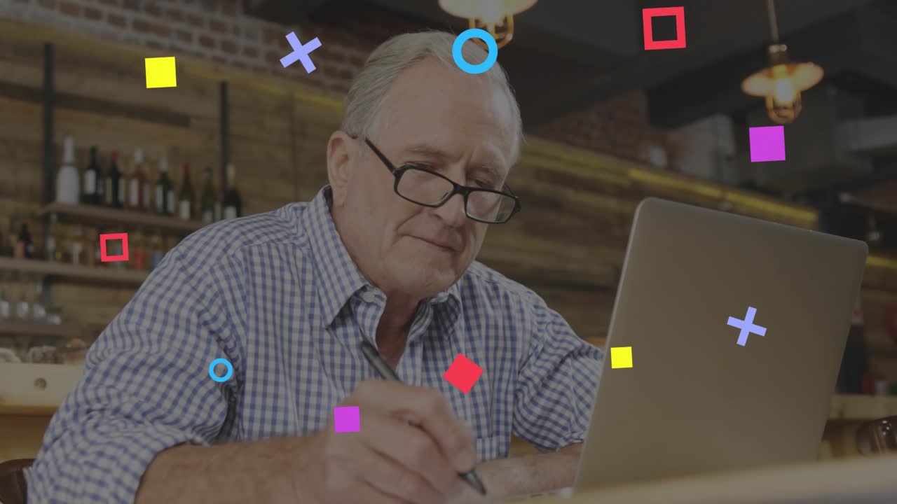 Senior man placing pen near laptop jotting notes while shapes swirling above sparking ideas in tech