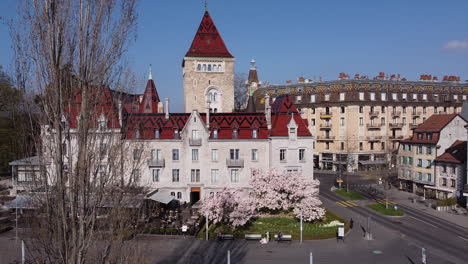 Rotating-aerial-shot-in-front-of-a-large-hotel-built-on-the-site-of-an-old-medieval-castle-in-Lausanne,-Switzerland-on-a-sunny-day