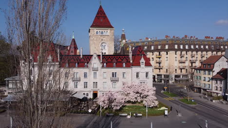toma aérea giratoria frente a un gran hotel construido en el sitio de un antiguo castillo medieval en lausana, suiza en un día soleado