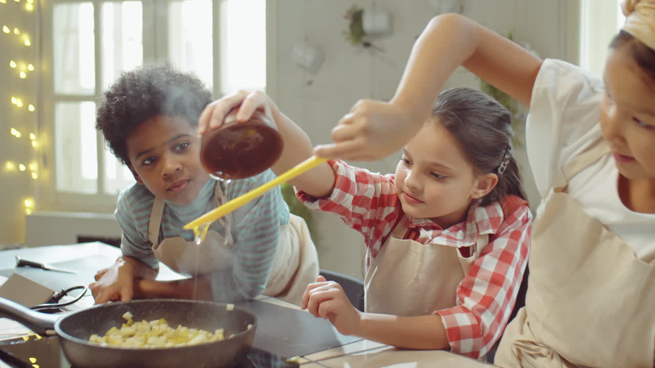 niños añadiendo miel a la fruta en la sartén durante la clase de cocina