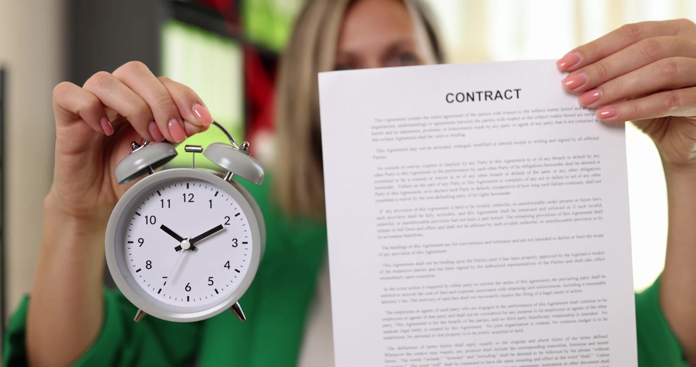 A woman holds a contract and an alarm clock a closeup