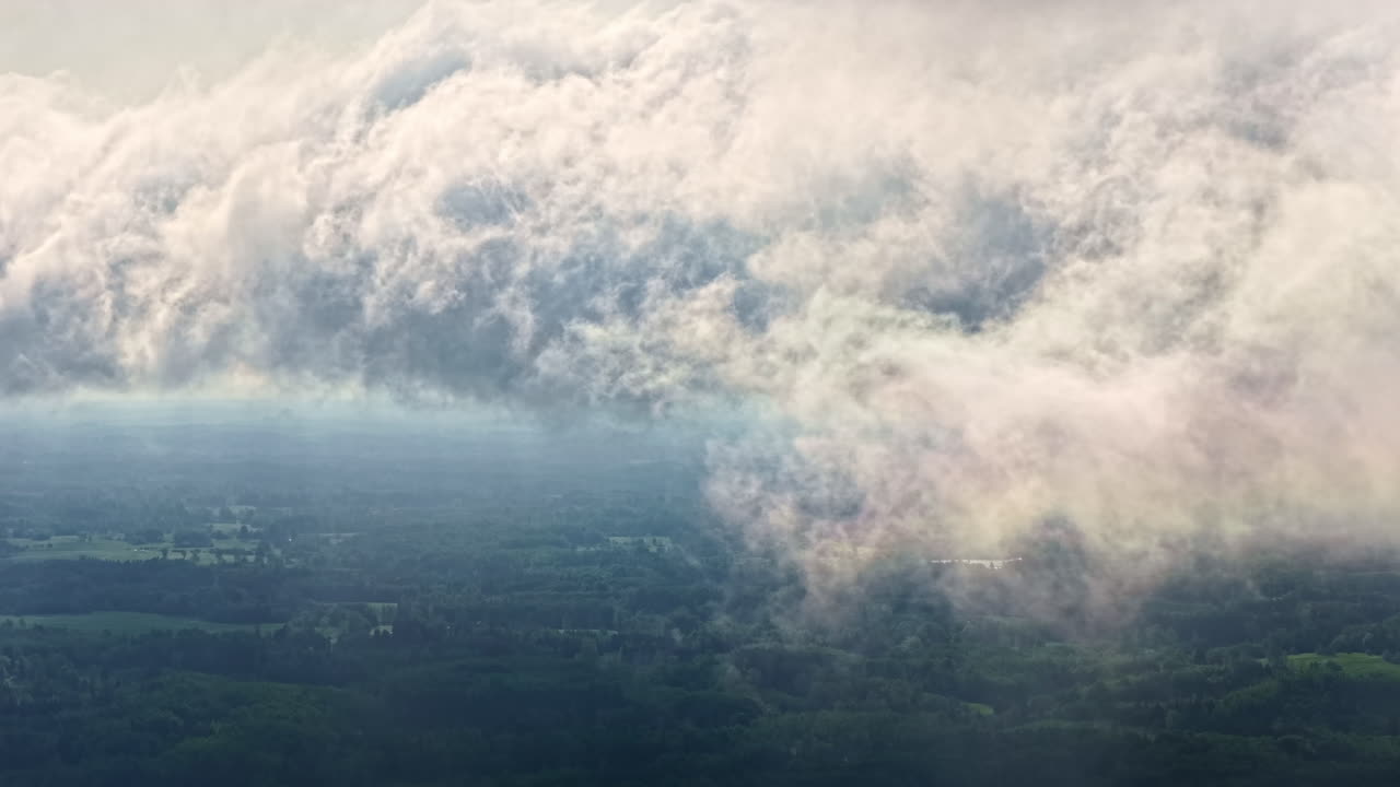 Misty clouds rolling over green fields, captured from above with a serene landscape