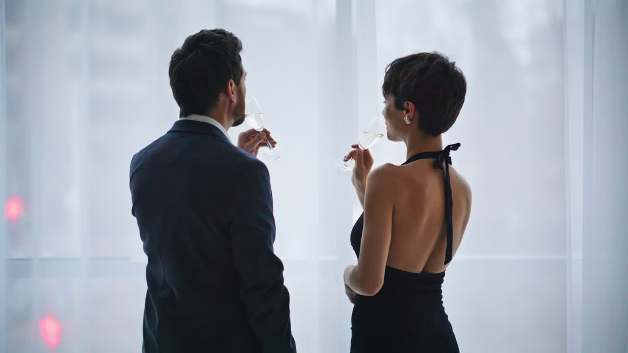 Primo piano: coppia romantica chiacchiera con vista sulla città sorseggiando alcolici in hotel. Coppia ad un appuntamento.