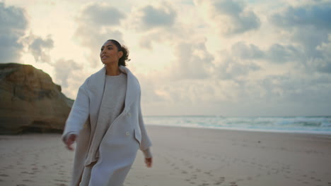 mujer atractiva girando playa del océano. modelo de cabello negro disfrutar del momento brazos abiertos