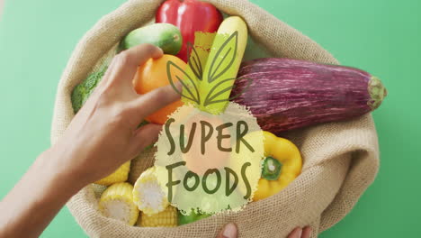 hands holding burlap sack of vegetables with super foods animation over it