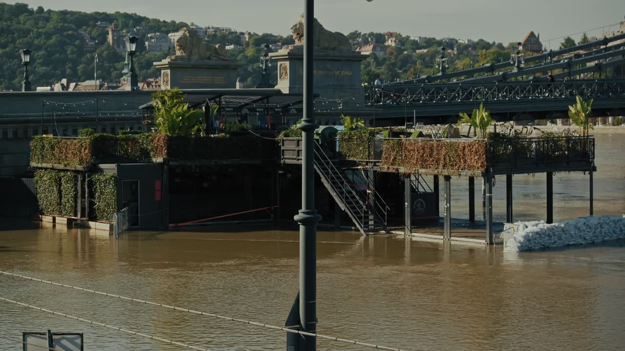 Flooded riverside restaurant protected by sandbags with nearby bridge in an urban area