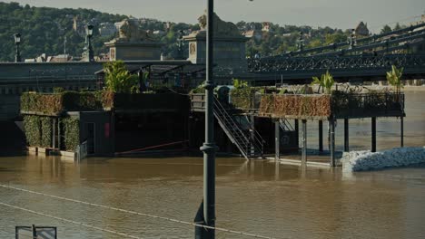 flooded riverside restaurant protected by sandbags with nearby bridge in an urban area