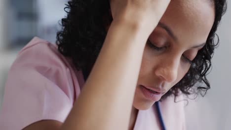 Stressed-biracial-female-nurse-leaning-on-wall-in-hospital-in-slow-motion