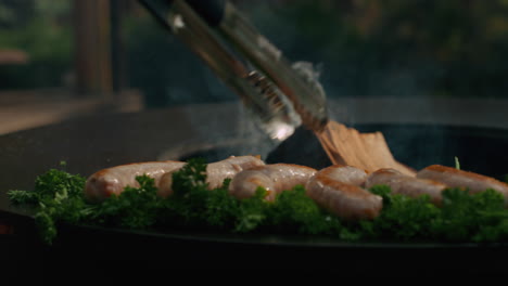 man moving apart sausages with forceps on grill. chef preparing sausages