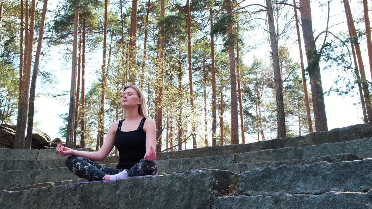 una mujer meditando en un bosque.