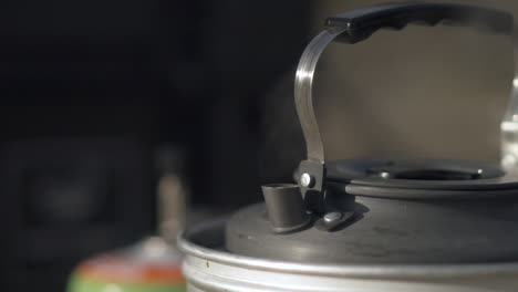 hervidor de agua hirviendo en estufa de camping de gas, primer plano de vapor caliente