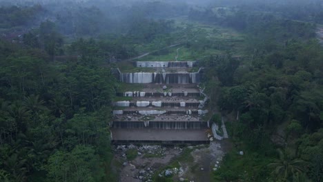 Cinematic-orbit-of-Watu-Purbo-waterfall,-forest-shrouded-in-fog