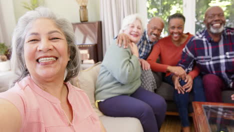 Glückliche-ältere-Kaukasische-Frau,-Die-Selfie-Mit-Verschiedenen-Freunden-In-Sonnigem-Zimmer-Macht,-Zeitlupe