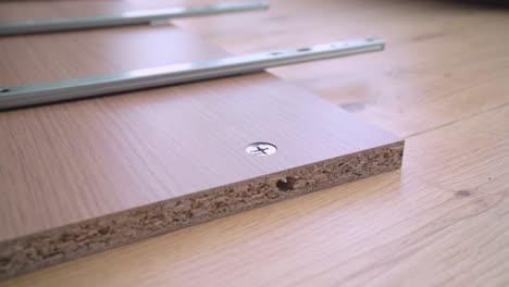 handyman assembling a cam lock on a wooden furniture with sled rails