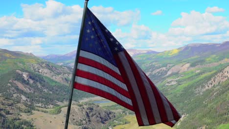 us flag waving on mountaintop over a lush green valley