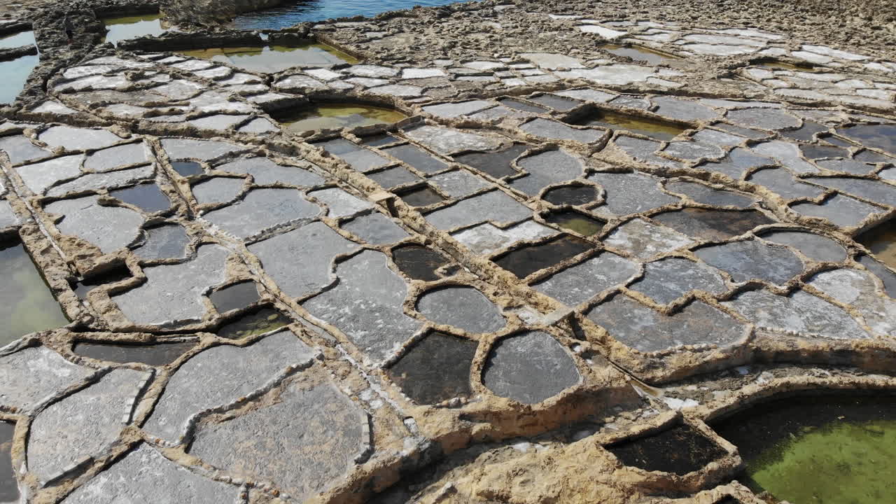 A slow, low-level aerial drone shot skims across the Salt Pans of Gozo island in Malta.