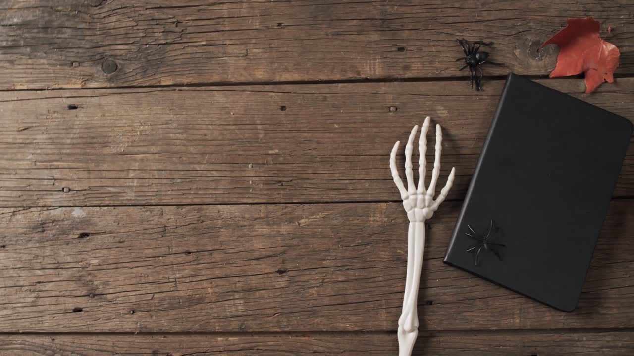 Video af halloween-skelethænder, notesbog og dekorationer med plads til tekst på træbaggrund