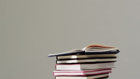 close up of open book on stack of books on grey background, in slow motion